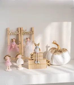 Pink and white Christmas angel figurines and gnome decor on a festive wooden display