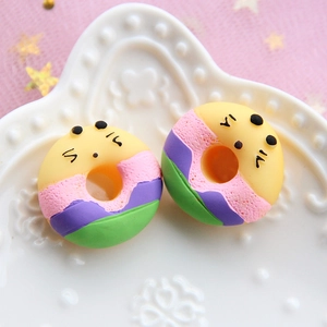 Macro shot of colorful resin donut charms for DIY crafts on a white embossed plate