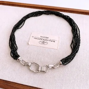 Collier multi-rangs en perles noires avec fermoir argenté texturé sur carte vintage