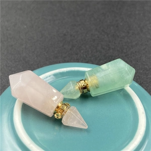 Detailed macro view of pink and green crystal perfume pendants on a ceramic plate