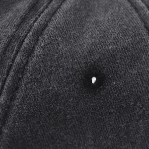 Macro shot of dark grey washed cotton fabric with stitched eyelet on a baseball cap