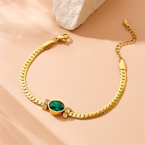 Gold chain bracelet with green oval gemstone and diamonds on a neutral stone display