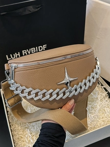 Macro shot of khaki lychee leather chest bag with bold silver chain and cross star detail