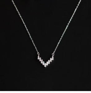 Macro shot of V-shaped sterling silver necklace with baguette-cut zircon inlays