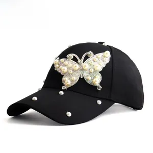 Detail shot of the giant pearl butterfly embroidery on a black cotton baseball cap