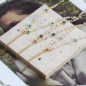 Detailed view of three evil eye pearl bracelets on a stone tile background