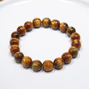Handmade beaded bracelet with 10mm tiger eye stone beads on a white ceramic display tray