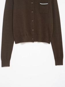 Close-up of brown knit cardigan featuring button closure and blue striped pocket detail