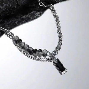 Macro shot of silver double chain necklace with marble beads and black zircon pendant