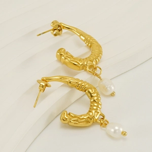 Detail of U-shaped gold earrings with irregular lava texture and hanging pearl drop