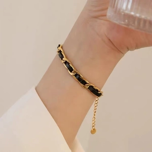Detail of gold metal chain interwoven with black leather strap and adjustable clasp