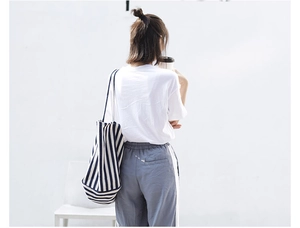 Vertical blue and white striped canvas tote bag styled with casual outfit for a minimalist look
