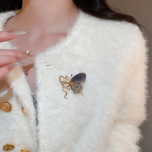 Detail of a purple fabric and gold butterfly brooch with rhinestones on a sweater
