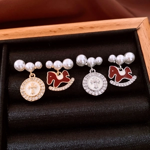 Detail of luxury pearl and zircon brooches featuring cross and rocking horse designs