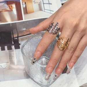 Close-up of gold and silver irregular hollow rings worn on hand with chic nail art