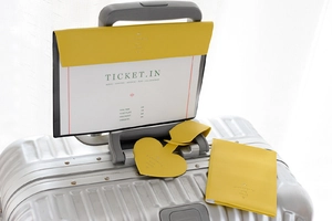 Detail of yellow faux leather travel set with heart-shaped luggage tag and passport holder