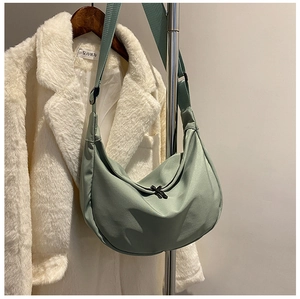 Detailed view of mint green crescent nylon crossbody bag on a hanger with wide strap