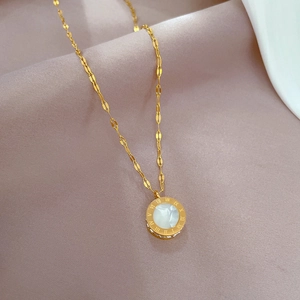 Detail of gold titanium necklace with Roman numerals and white shell inlay on a soft background