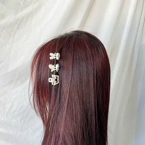 Detail of cream butterfly hair clips and pearl claw clip on straight red hair