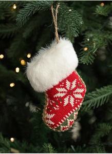 Detail of a knitted red Christmas stocking ornament with snowflake pattern and fur trim