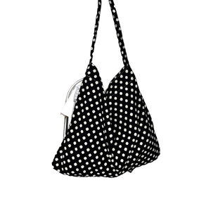 Minimalist black canvas tote bag with white polka dot pattern and slim shoulder straps