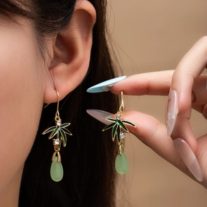 Detail of bamboo leaf earrings with green water drop pendants and sparkling crystal accents