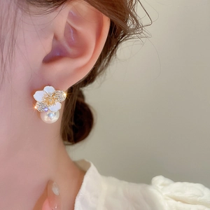 Close-up of zircon flower stud earrings with a dangling pearl on a female model