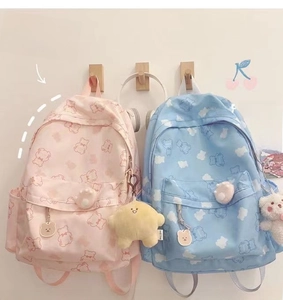 Close-up of pastel nylon backpacks with cute bear prints and plush star accessories