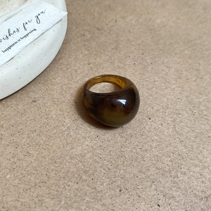 Detail shot of a polished amber resin oval ring on a natural brown paper background