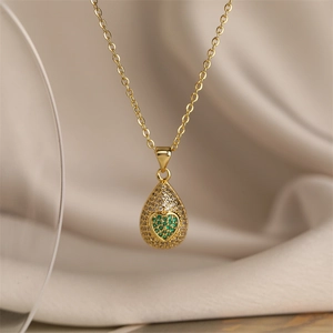 Macro d'un pendentif goutte plaqué or avec pierre cœur verte et détails en zircon blanc