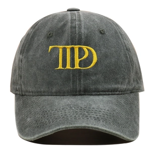 Close-up of yellow embroidered letters on a dark grey washed cotton baseball cap
