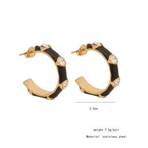Detailed macro view of black enamel gold-plated stainless steel earrings with white crystals