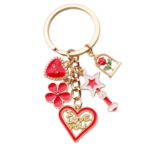 Cute golden heart keychain with red enamel rose and magic wand charms on white background