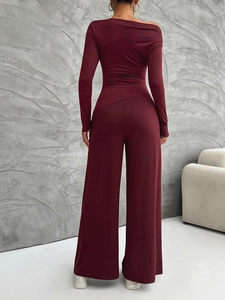 Back view of burgundy two-piece set featuring long sleeve asymmetric top and wide leg pants