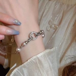 Gros plan d'un bracelet en perles avec fermoir anneau serti de zircons au poignet