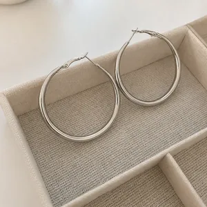 Minimalist silver circular hoop earrings in a wooden jewelry box with linen lining