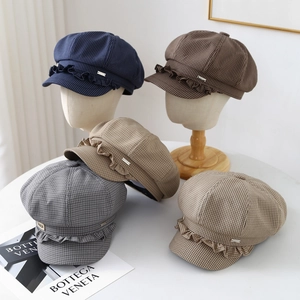 Detailed view of checkered newsboy caps with ruffle trim and metal logo accents