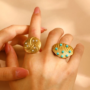 Detail of gold spiral ring with crystals and a shell ring with turquoise beads