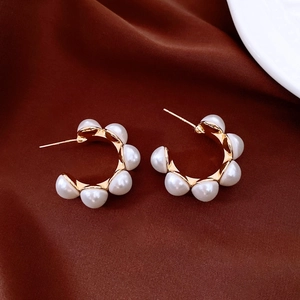 Détail de boucles d'oreilles C plaquées or avec perles sur fond en soie rouge