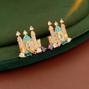 Detailed close-up of gold-plated castle earrings with multi-colored crystals on velvet