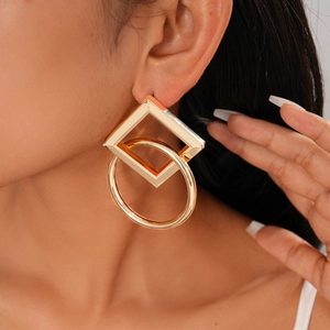 Close-up of geometric square and circle interlocking metal earrings worn by a model