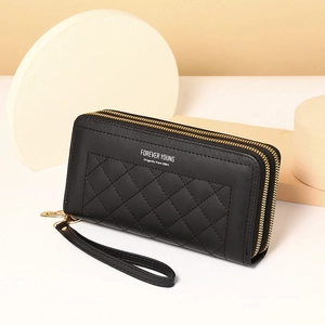 Macro view of black quilted leather long wallet featuring dual gold zippers and wristlet