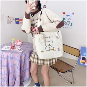 Detail of a beige corduroy tote bag featuring a cute blue cartoon bear and embroidery