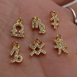 Gold zodiac pendants with sparkling zircon stones for jewelry making shown in hand