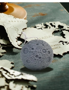 Macro shot of 3D moon scented candle with realistic crater texture on world map background