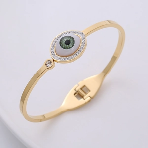 Detail of gold evil eye spring bracelet with green opal iris and crystal accents