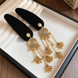 Ethnic style golden tassel earrings with jhumka bells on black velvet display stand