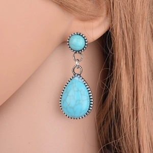 Close-up of bohemian turquoise earrings featuring silver filigree and teardrop charms
