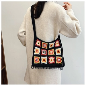 Detailed view of back-carried knit shoulder bag with granny square patterns and tassels