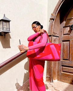 Close-up of a large magenta tote bag with geometric patterns held by a model in a city street